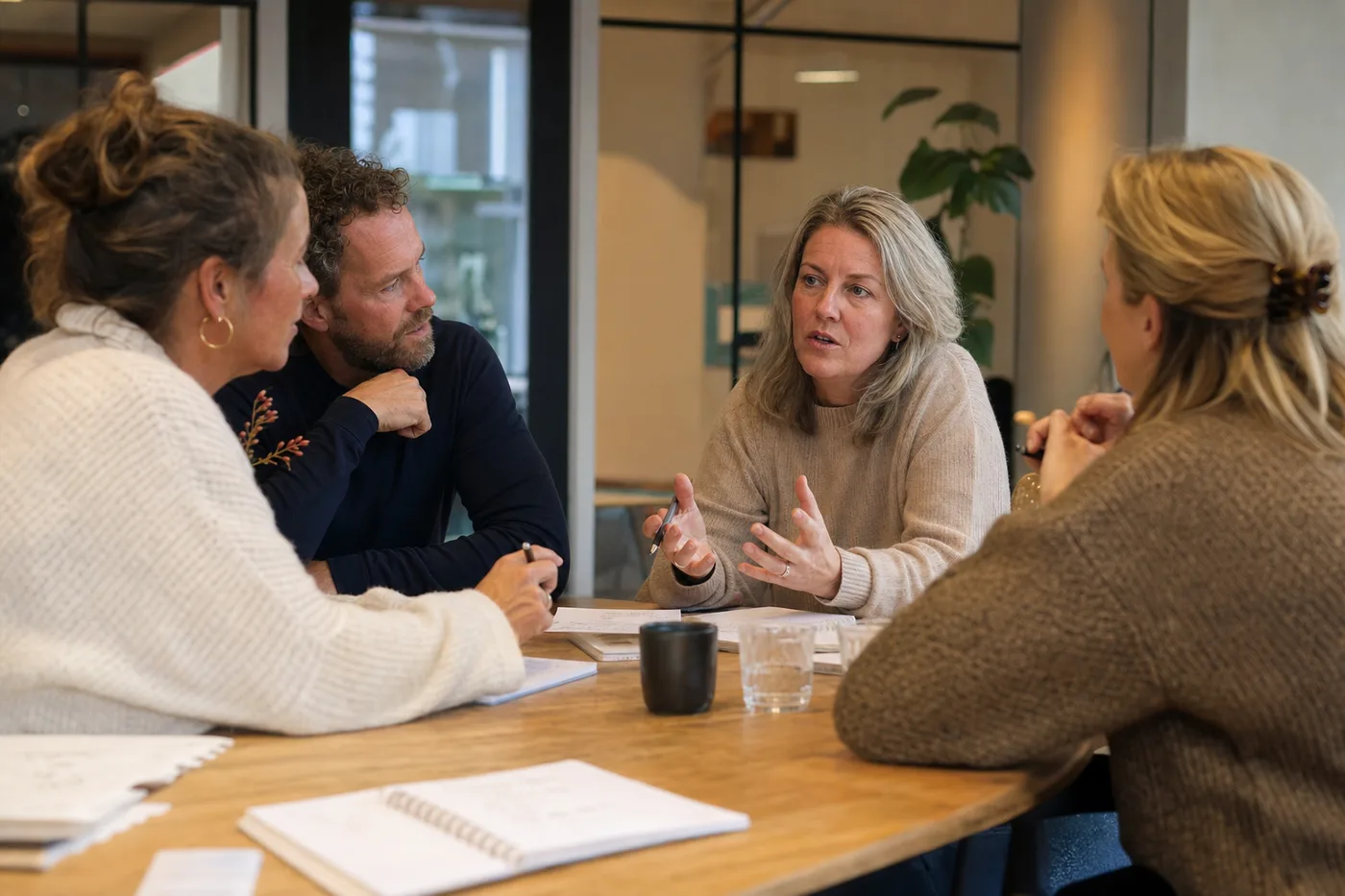 Collega's overleggen rond een tafel met aantekeningen